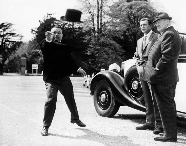 Oddjob (Harold Sakata, l.) demonstrates his lethal hat skills to Bond and Goldfinger (Gert Frobe)